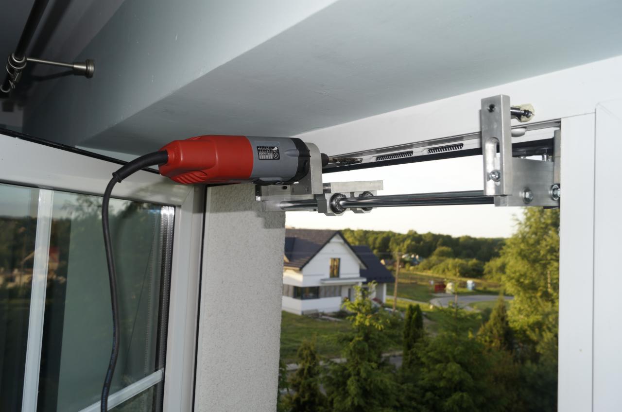 Montaż automatycznego otwierania okna balkonowego za pomocą wiertarki z adapterem. Widok na zewnątrz, dom w tle. Specyficzny adapter do wiertarki.