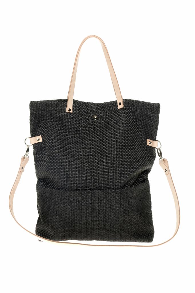Czarna, tkana torba shopper z jasnymi, skórzanymi uchwytami i paskiem na ramię, na białym tle. Widoczne detale mocowań paska.