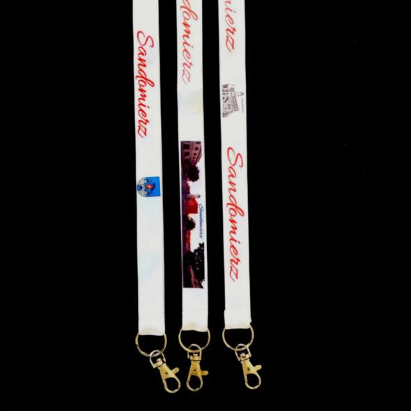 Trzy białe smycze z nadrukiem Sandomierza i lokalnymi symbolami na czarnym tle, z metalowymi karabińczykami. Nadruk wykonany w kolorze czerwonym i niebieskim.