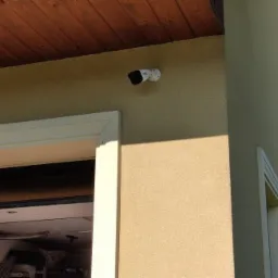 Kamera monitoringu zamontowana na elewacji budynku w Bochni, widok z boku, z widocznym fragmentem garażu.