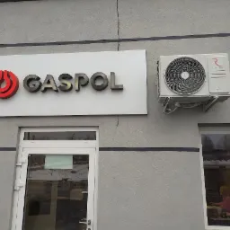 Elewacja budynku z klimatyzatorem Rotenso obok szyldu firmy GASPOL, widoczne okna i drzwi wejściowe.