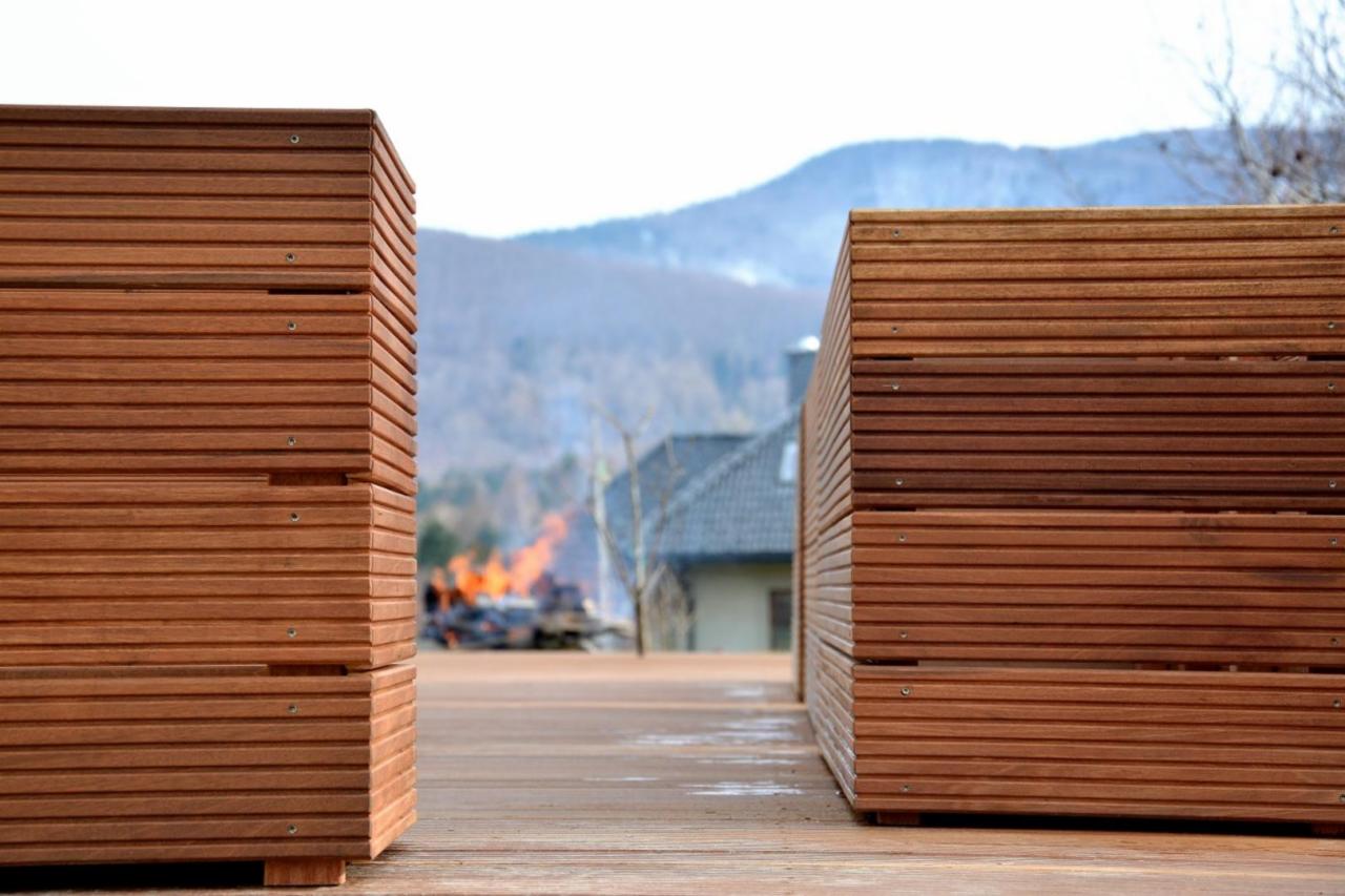 Drewniany taras z zabudową w formie donic z desek na tle gór i ogniska. Widoczne detale montażu i faktura drewna.