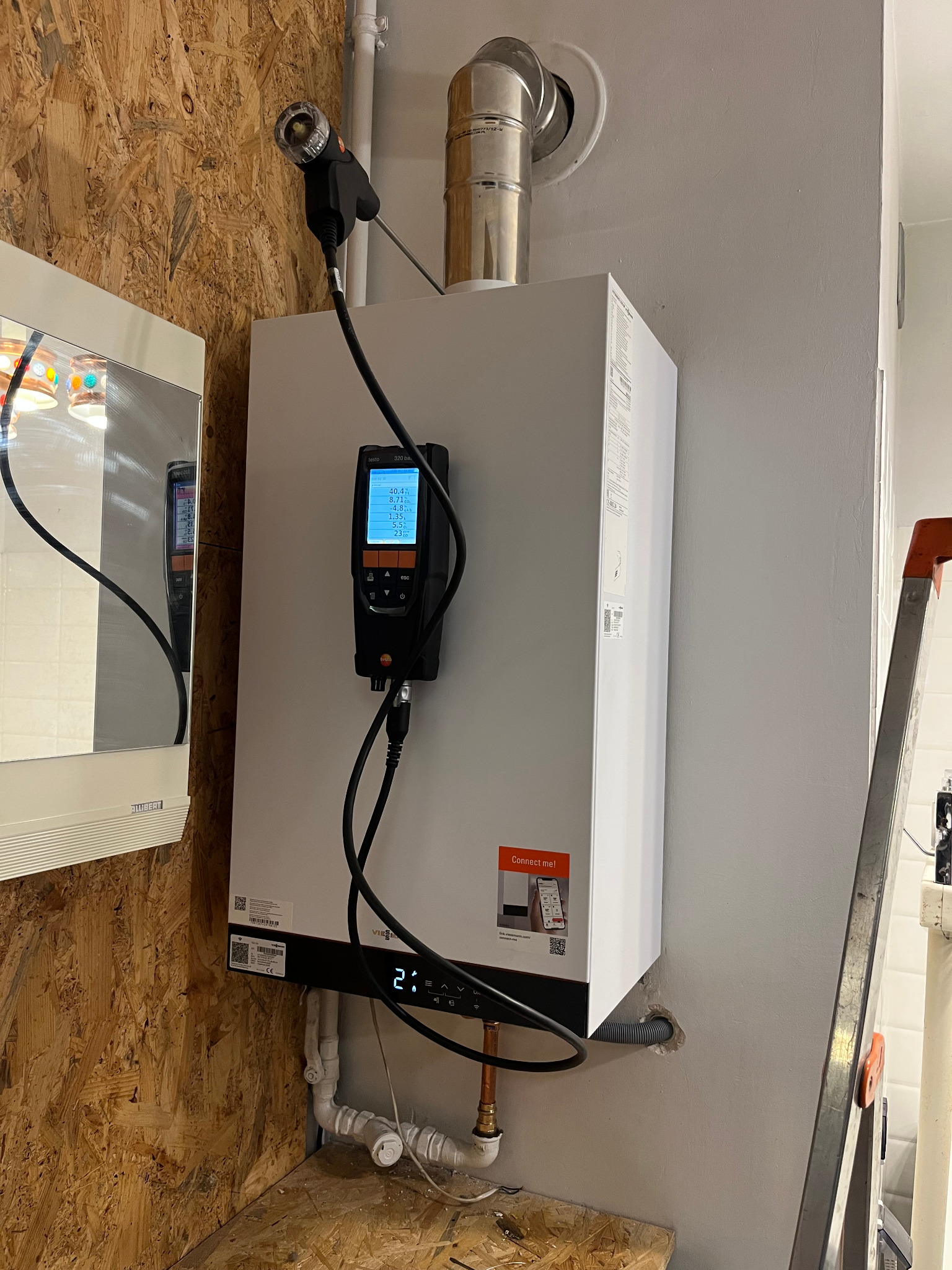 Biały piec gazowy marki Viessmann zamontowany na ścianie w Bytomiu, podłączony do komina i instalacji, z podłączonym analizatorem spalin Testo 320 ba, widoczna drabina oparta o ścianę.