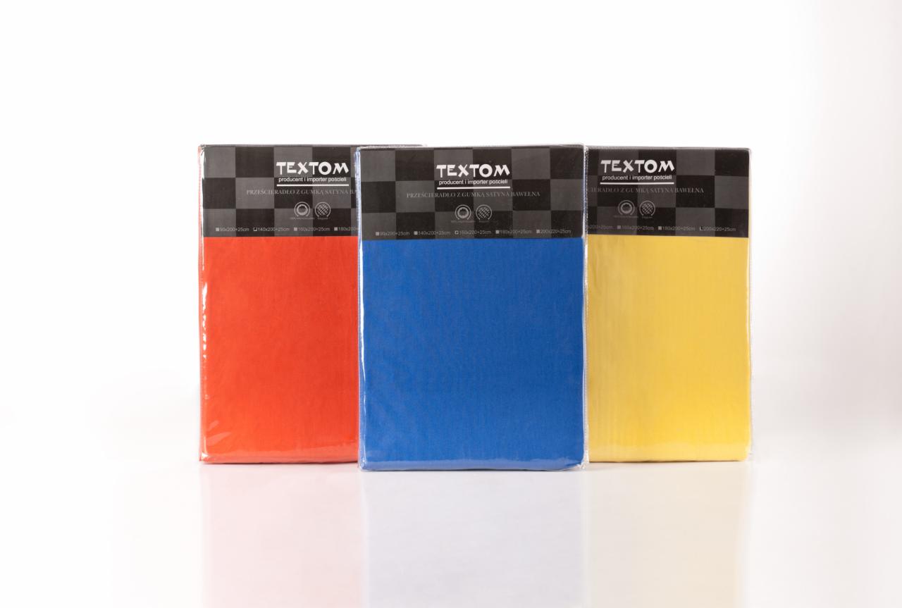 Trzy opakowania prześcieradeł z gumką marki TEXTOM w kolorach: pomarańczowym, niebieskim i żółtym, na białym tle z odbiciem.