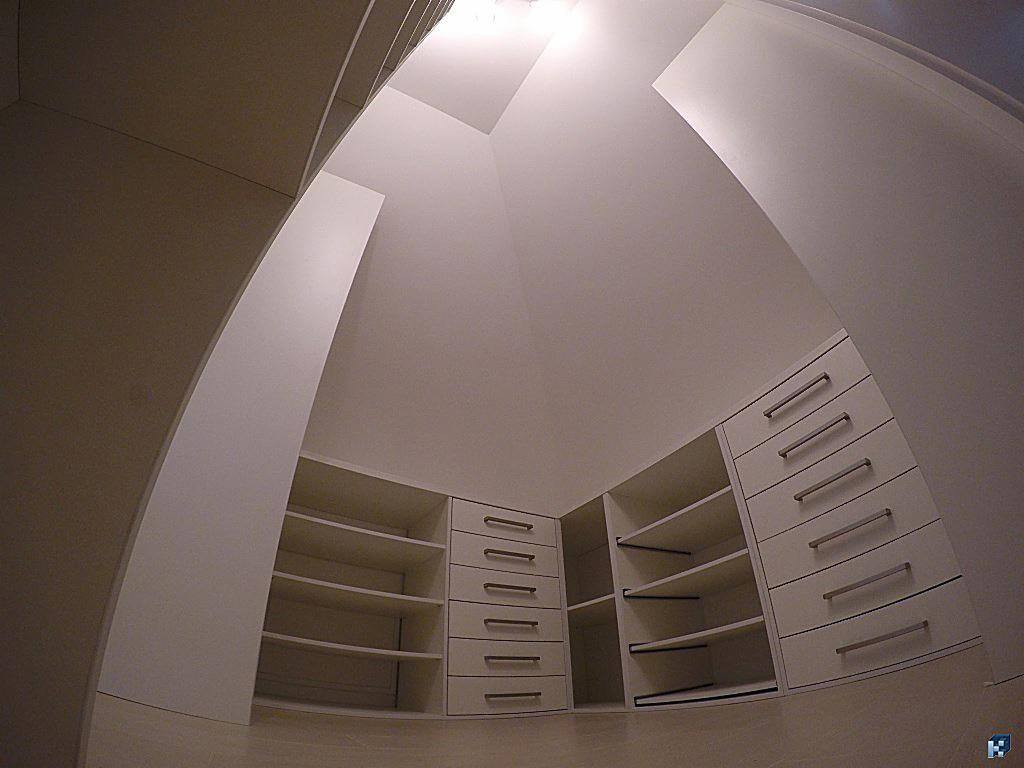 Biała zabudowa szafy wnękowej z szufladami i półkami, dopasowana do skosu poddasza. Nietypowy układ, widok z dołu z efektem rybiego oka.