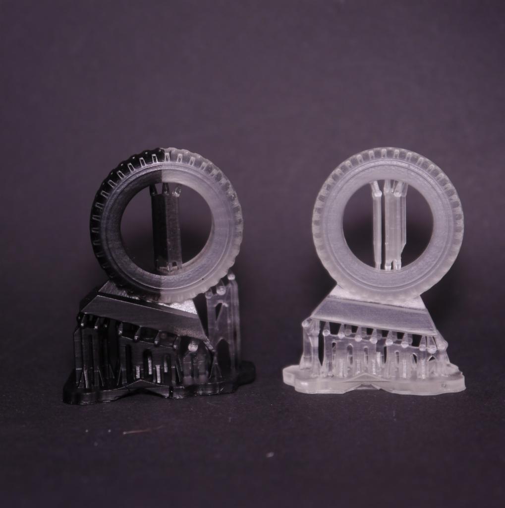 Dwa wydruki 3D w odcieniach szarości przedstawiające model koła z podporami, widoczne ślady warstw druku.