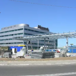 Budowa stacji paliw z metalową konstrukcją w tle budynku Microsoft w Warszawie, widoczne materiały budowlane i maszyny.