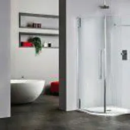 Nowoczesna łazienka z wolnostojącą wanną, przeszkloną kabiną prysznicową z chromowanymi uchwytami i półkami ściennymi z dekoracjami w kolorze czerwonym i zielonym.