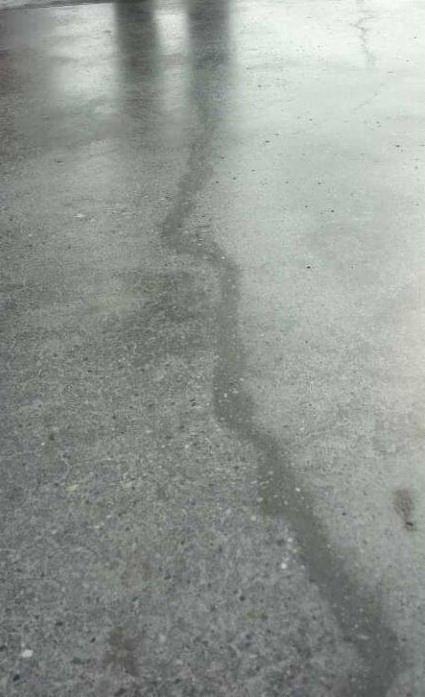 Szlifowana, betonowa posadzka przemysłowa z widocznym pęknięciem, odbijająca światło z góry.