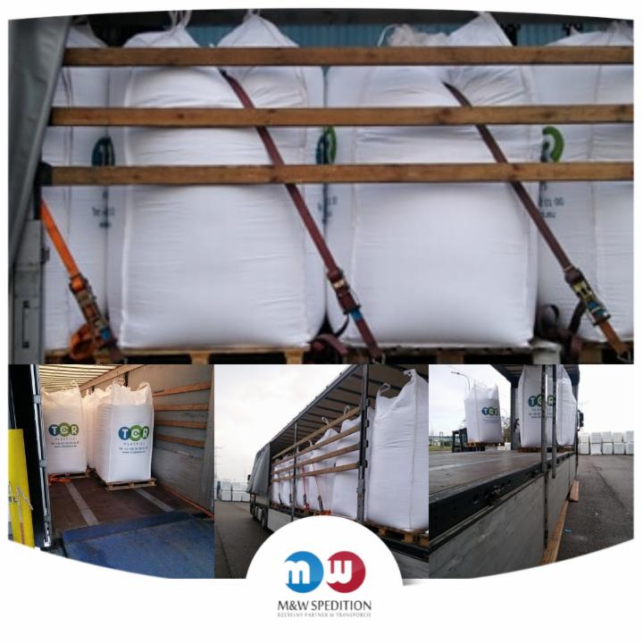 Wnętrze naczepy wypełnione paletami z dużymi, białymi workami zabezpieczonymi pasami transportowymi; widoczne logo firmy spedycyjnej.