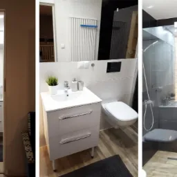 Wnętrze nowoczesnej łazienki z kabiną prysznicową typu walk-in, białą umywalką z szafką i wiszącą toaletą, wykończone płytkami w odcieniach bieli, szarości i czerni z elementami drewnianymi.