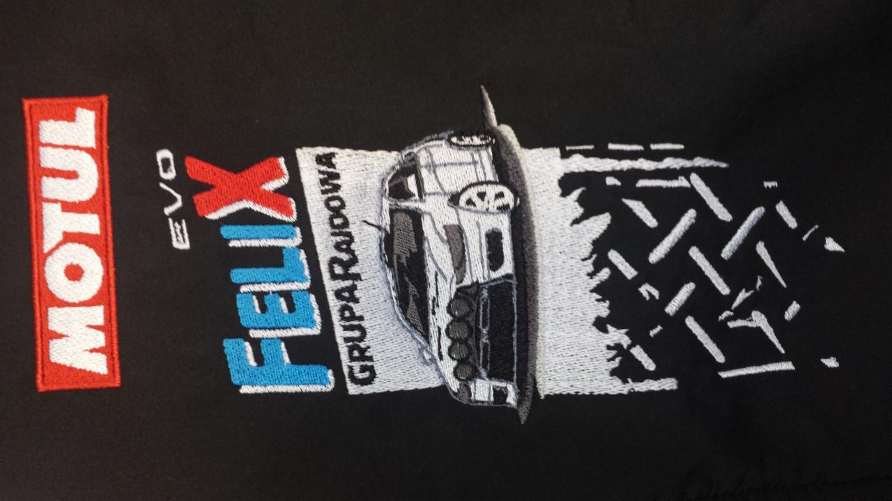 Haftowany wzór na czarnej tkaninie: logo Motul, napis Felix Grupa Rajdowa i grafika auta rajdowego z efektem śladów opon. Precyzyjne detale haftu.