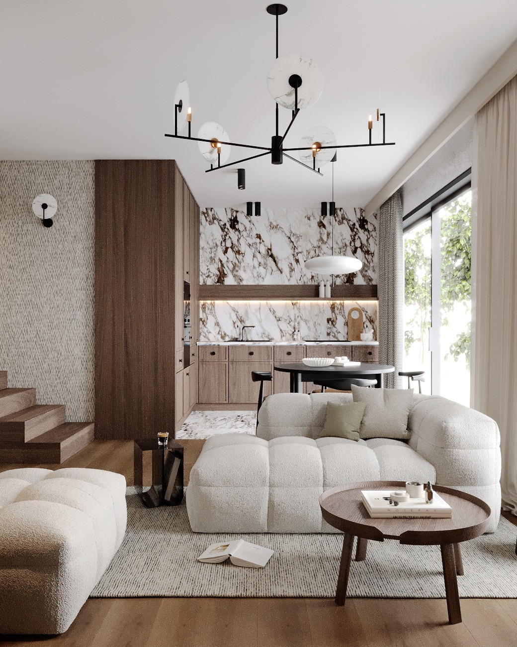 Jasny salon z otwartą kuchnią, marmurowa ściana nad blatem, nowoczesna lampa sufitowa z okrągłymi kloszami, puszysty narożnik i drewniany stolik kawowy z książkami.