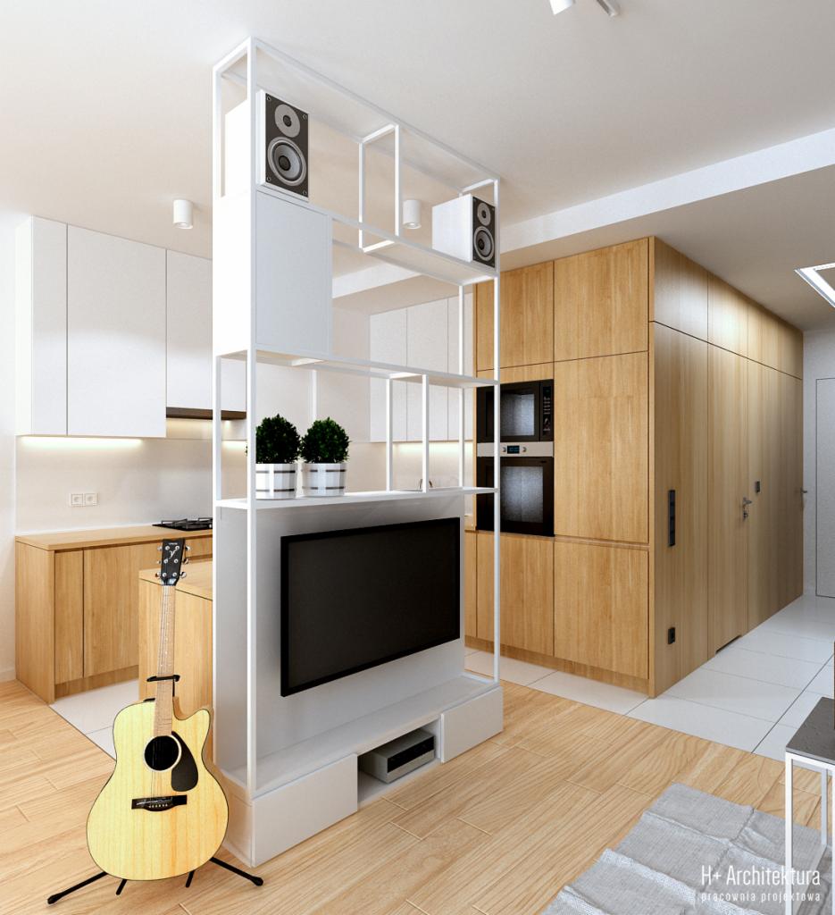 Nowoczesne wnętrze z otwartą kuchnią, drewnianymi szafkami, białą ścianką działową z telewizorem i głośnikami, oraz gitarą akustyczną na statywie.
