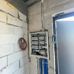 Rozdzielnica przy wejściu na etapie montażu. Kable w peszlach uporządkowane, gotowe do podłączenia osprzętu