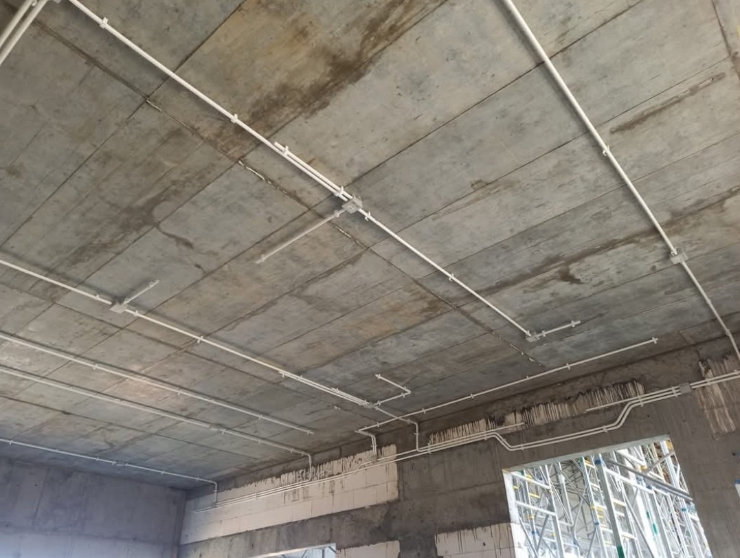 Instalacja w hali – równe linie rur na suficie, przewody schowane i zabezpieczone, gotowe pod oświetlenie