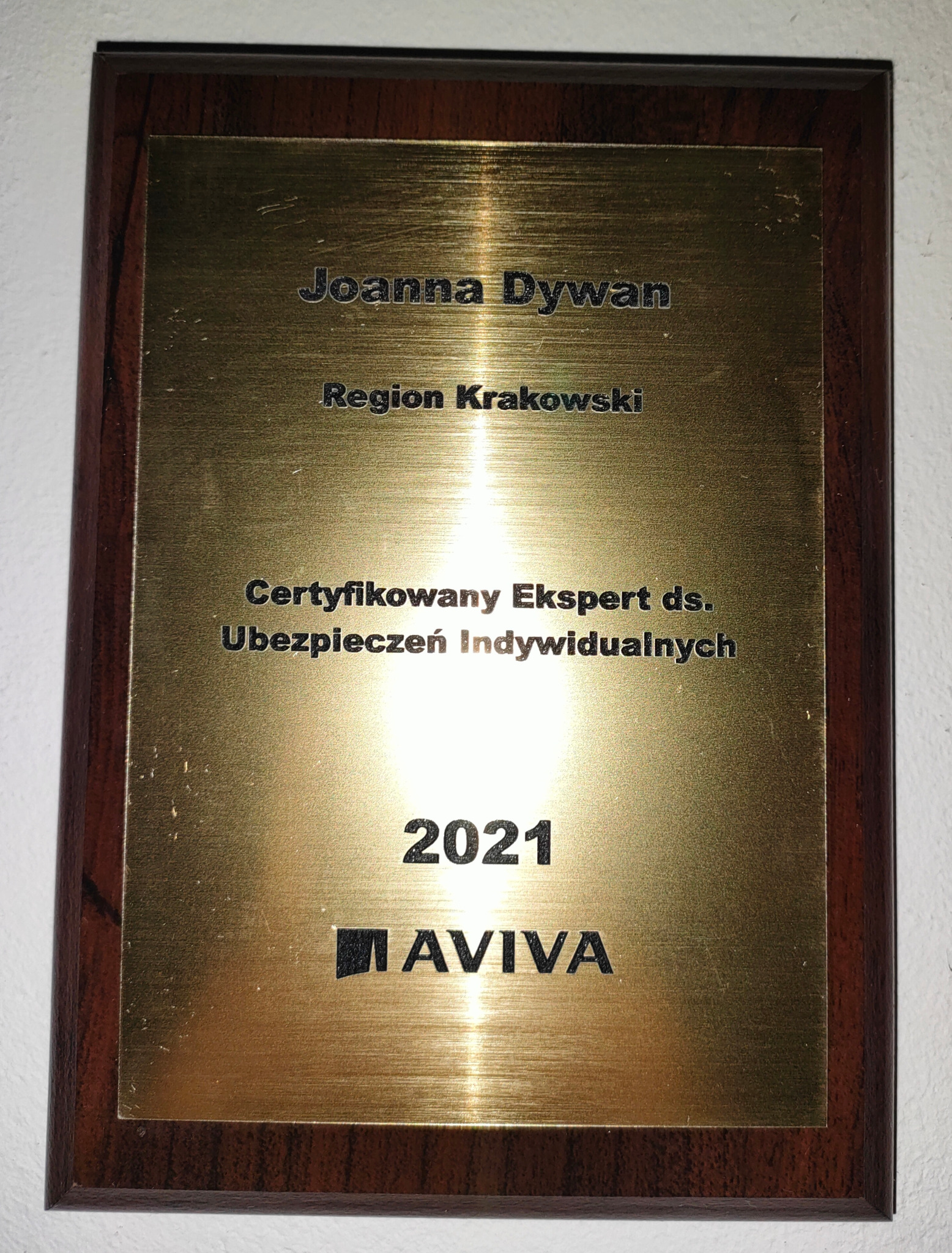 Certyfikat eksperta ds. ubezpieczeń indywidualnych Joanna Dywan, region krakowski, rok 2021, logo Aviva, oprawiony w drewnianą ramkę.