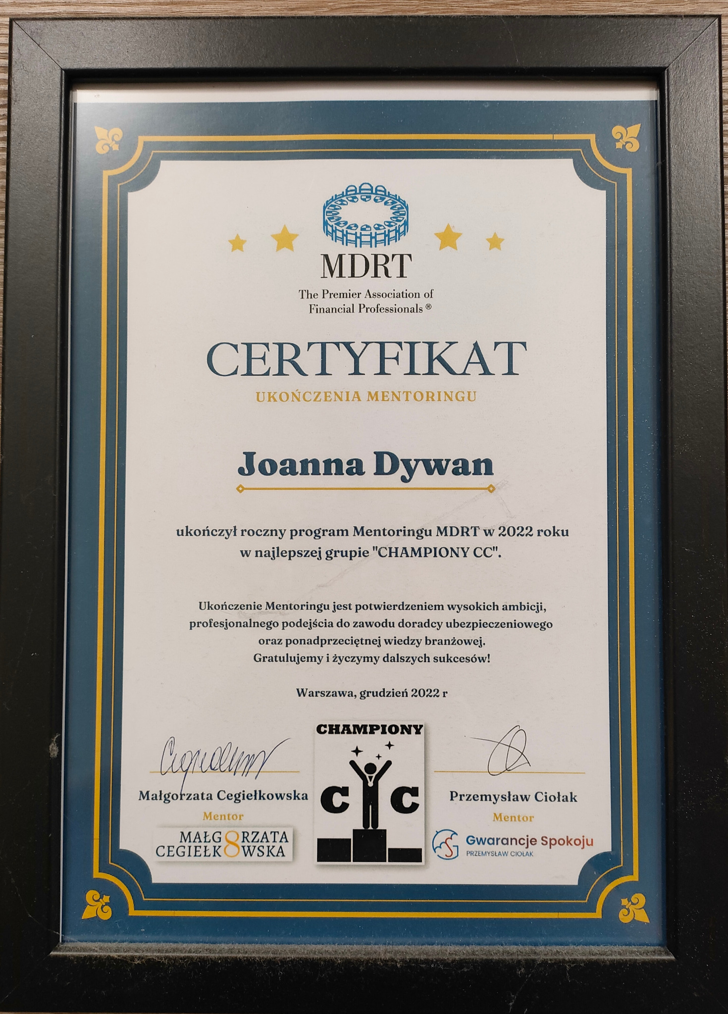 Oprawiony certyfikat MDRT dla Joanny Dywan za ukończenie mentoringu w 2022 roku, potwierdzający wysokie ambicje i profesjonalizm w doradztwie ubezpieczeniowym.