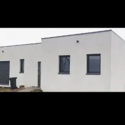 Nowoczesny, parterowy dom z białym tynkiem, czarnymi ramami okiennymi i roletami, z widocznym koszem na śmieci przy ścianie.