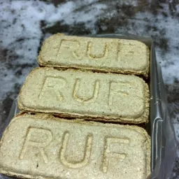 Trzy brykiety drzewne RUF ułożone w przezroczystym opakowaniu na tle śniegu.