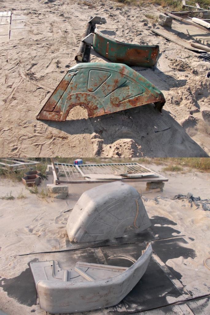 Zardzewiałe, zielone błotniki samochodowe leżące na piasku, niektóre po czyszczeniu, ukazują proces renowacji. Widoczne narzędzia i osprzęt.