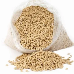 Worek przezroczystego plastiku wypełniony jasnymi, cylindrycznymi granulkami, z wysypaną kupką tych samych granulek na białym tle.