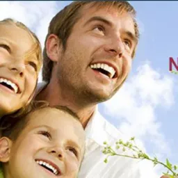 Uśmiechnięta rodzina (ojciec i dwie córki) patrzy w górę na tle błękitnego nieba i zieleni. Tekst: Zadbaj o szczęście najbliższych.