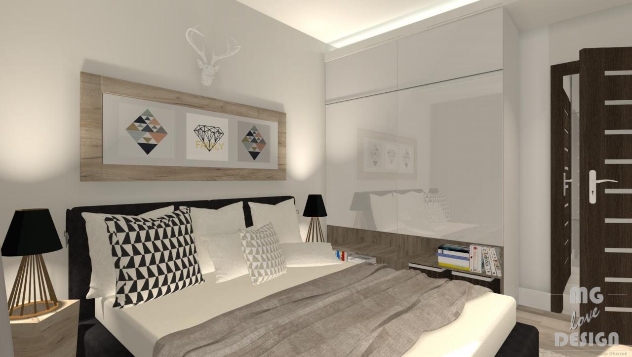 Jasna sypialnia z łóżkiem, szafą z lustrzanymi drzwiami i drewnianą ramą nad łóżkiem z trzema obrazkami w geometryczne wzory, oraz dekoracyjną głową jelenia na ścianie.
