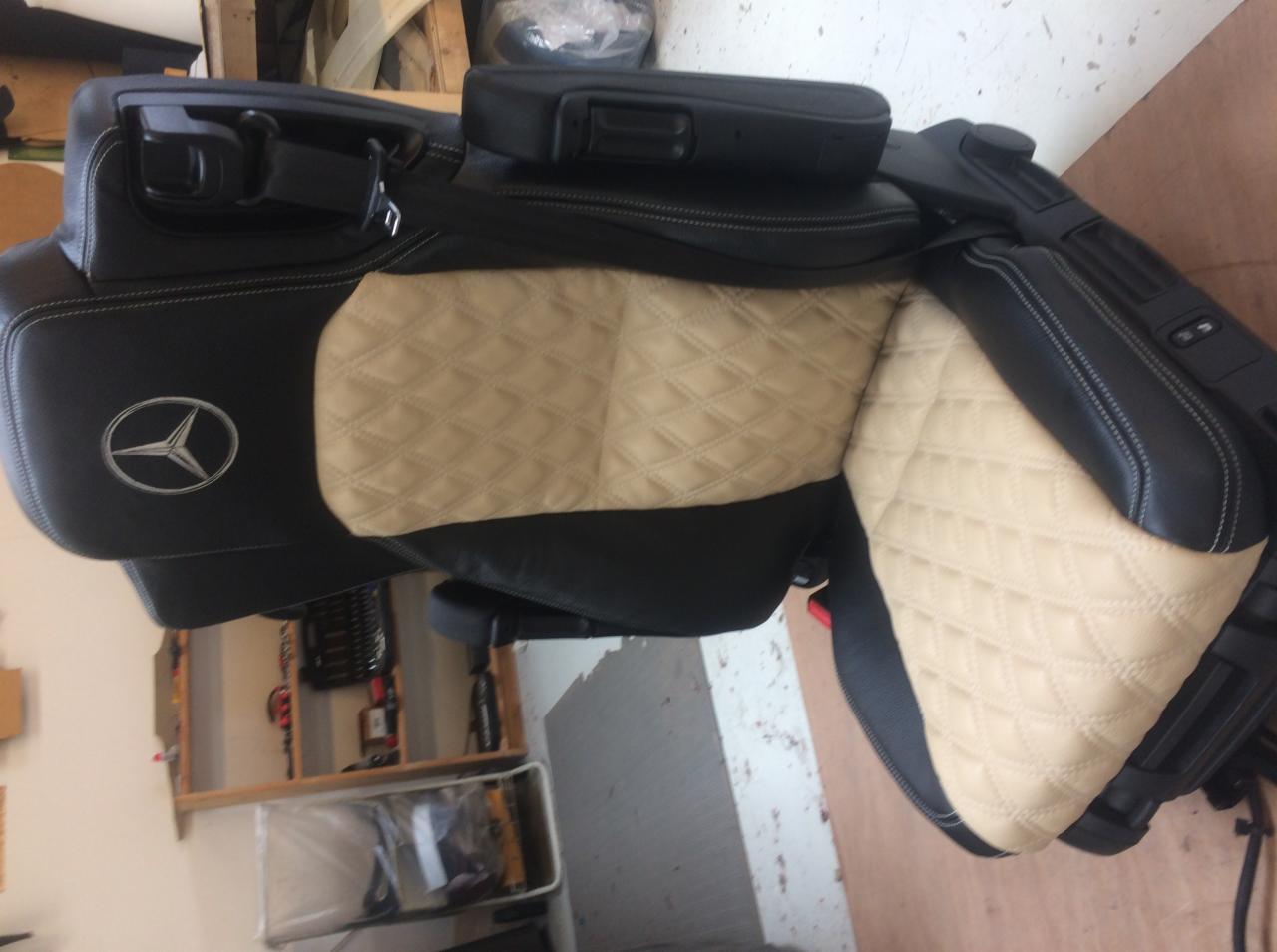 Tapicerowane na czarno elementy wnętrza samochodowego Mercedes z beżową, pikowaną skórą w romby, widoczne logo marki.