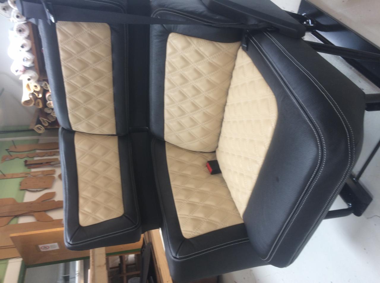 Odnowione tylne siedzenie samochodowe z czarną skórą i beżową, pikowaną w romby wstawką, widoczny pas bezpieczeństwa i białe przeszycia.
