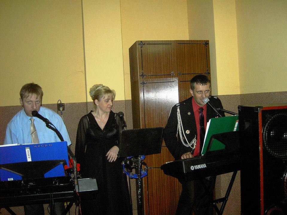 Występ zespołu muzycznego z Kolbuszowej: trzech muzyków gra na keyboardach i śpiewa do mikrofonów. Jeden z muzyków w mundurze.