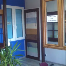 Ekspozycja w salonie: okno z brązową roletą zewnętrzną, białe okno z szybami refleksyjnymi, drzwi z żaluzjami poziomymi w odcieniach brązu i niebieskiego oraz drewniane okno z naklejką producenta...