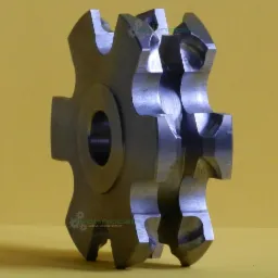 Precyzyjnie wykonany, metalowy frez ślimakowy na żółtym tle. Widoczne ostre krawędzie i otwór centralny. Detal obróbki CNC.