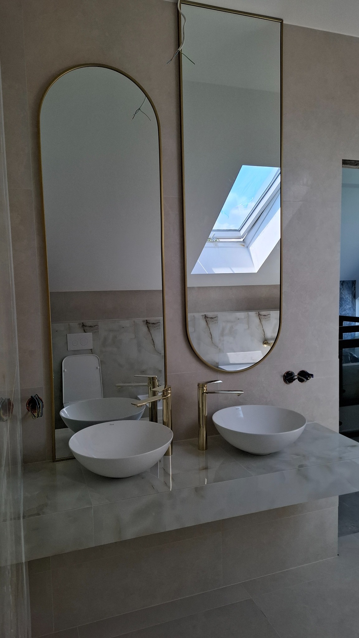 Wykończona łazienka w Stepnicy: dwie umywalki nablatowe z lustrami w złotych ramach. Minimalizm i elegancja w detalu.