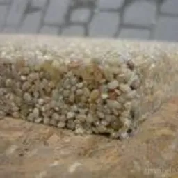 Przekrój przez wodoprzepuszczalną posadzkę z drobnych kamyczków na podłożu z płyty OSB, widoczne nierównomierne rozmieszczenie kamieni i struktura materiałów.