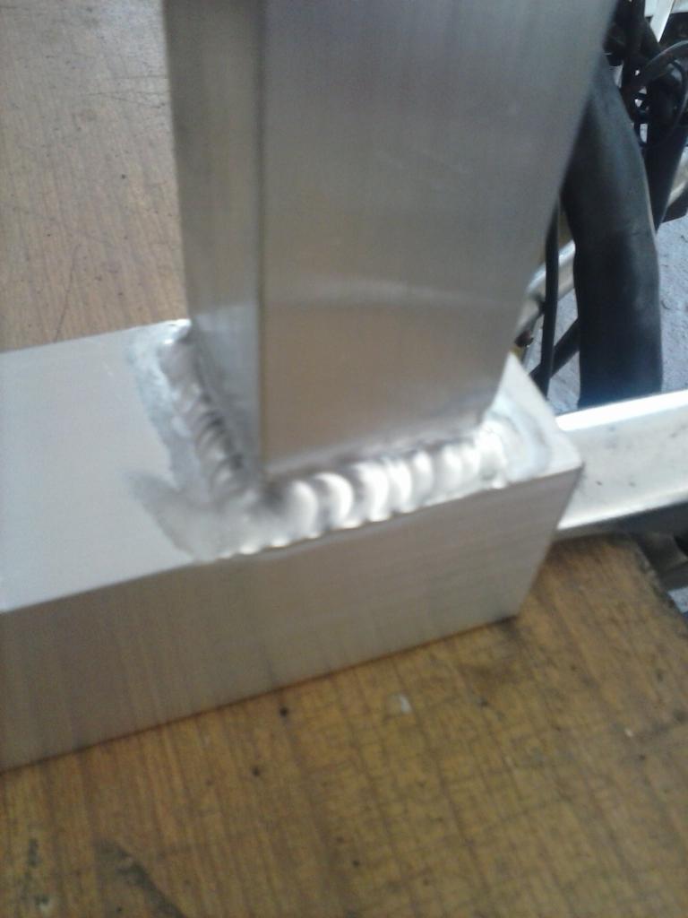 Szlifowany spaw na metalowej konstrukcji, widoczne ślady obróbki, surowe wykończenie. Detal spawu, zbliżenie na łączenie elementów.