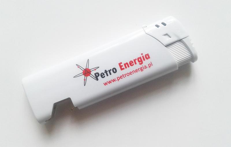 Biała zapalniczka z nadrukowanym logo Petro Energia i adresem strony internetowej, leżąca na białym tle. Widoczne detale i ostre krawędzie zapalniczki.