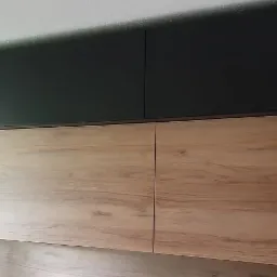 Nowoczesna szafa wnękowa z ciemnozielonymi górnymi szafkami i dolnymi szafkami z okleiną drewnopodobną, widoczna z dołu.