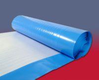 Rolka niebieskiej folii bąbelkowej na białej piance, kontrastowe tło w odcieniach czerwieni i szarości, widoczne pęcherzyki powietrza. Ochrona delikatnych przedmiotów.