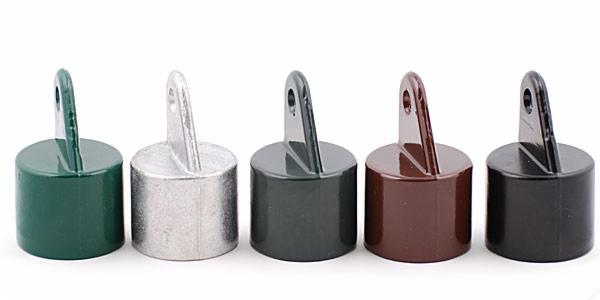 Kolorowe zaślepki słupków ogrodzeniowych z uchwytem, od zielonego po czarny, ułożone w rzędzie na białym tle. Różnorodność barw i materiałów.