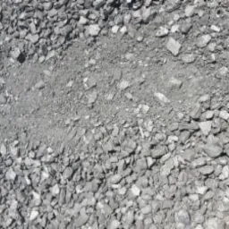 Szary, drobny węgiel kamienny w nasypie, z widocznym śladem po przesypaniu. Materiał o zróżnicowanej granulacji, od drobnego pyłu po większe bryłki.