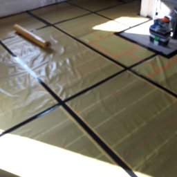 STELKAM.pl - Rozłożona folia grzewcza na podłodze, przygotowana do montażu, widoczny rolka folii i narzędzia w tle.