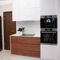 Nowoczesna kuchnia z białymi szafkami górnymi i dolnymi szafkami z forniru w odcieniach brązu, z wbudowanym ekspresem do kawy i piekarnikiem, na jasnej podłodze.