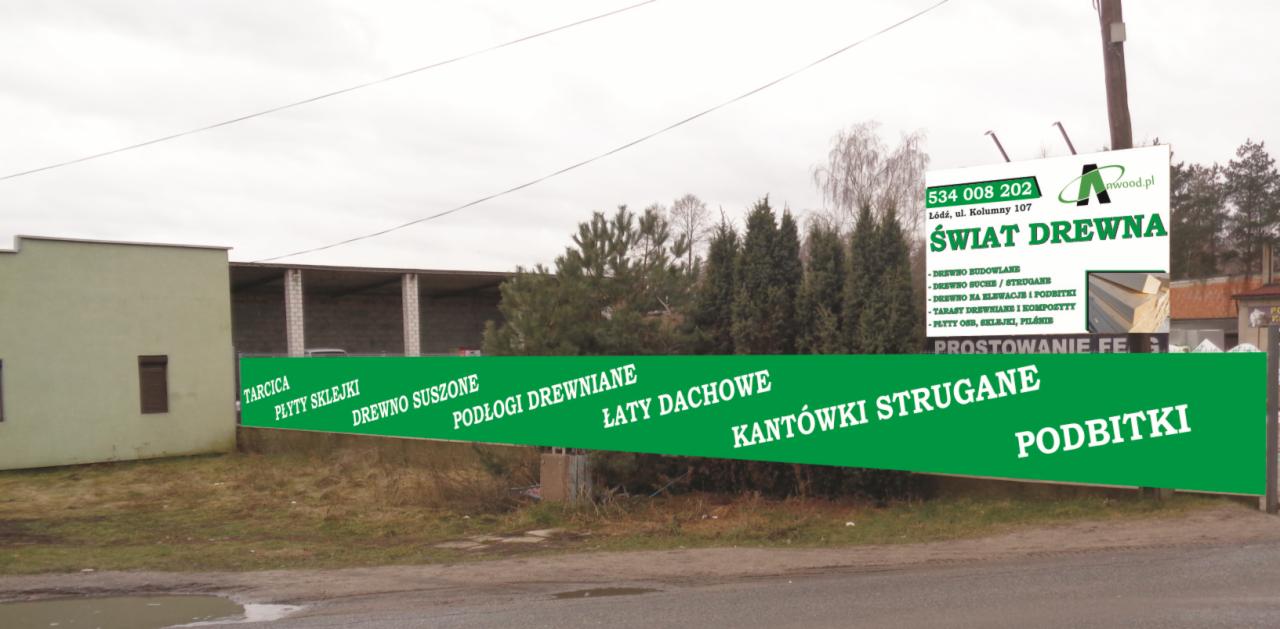 Zewnętrzny widok składu drewna z dużym banerem reklamowym prezentującym asortyment: tarcica, płyty sklejki, drewno suszone, podłogi drewniane, łaty dachowe, kantówki strugane, podbitki. Na banerze...