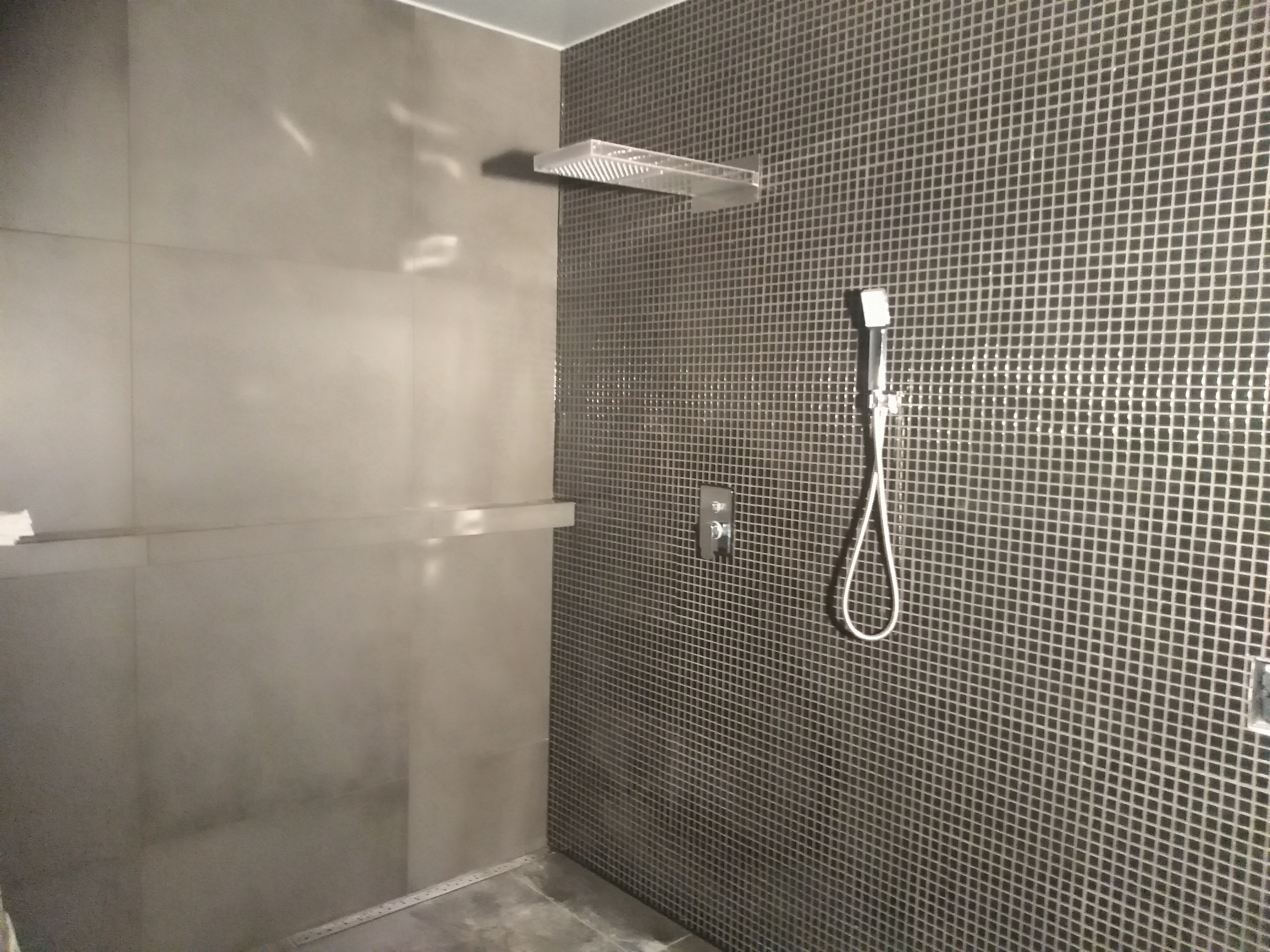 Wykończona kabina prysznicowa z deszczownicą i mozaiką w Żorach, widoczny panel sterowania i słuchawka prysznicowa.