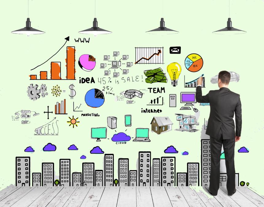 Mężczyzna w garniturze rysuje markerem na ścianie infografiki z wykresami, budynkami i symbolami biznesowymi, oświetlonej przez cztery lampy.