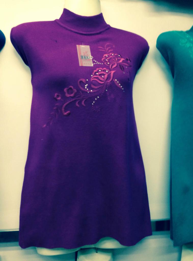 Fioletowa sukienka swetrowa z golfem, zdobiona haftem kwiatowym i koralikami, prezentowana na manekinie.