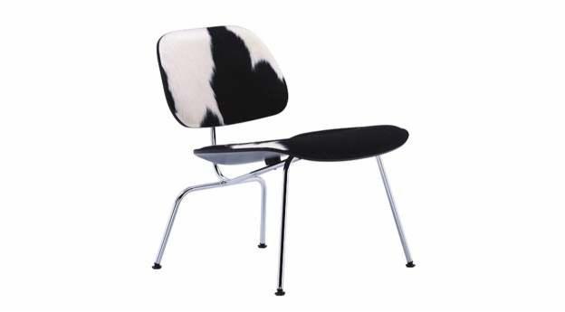 Krzesło z chromowanymi nogami i tapicerką w czarno-białą krowią łatę na oparciu i czarnym siedziskiem, na białym tle.