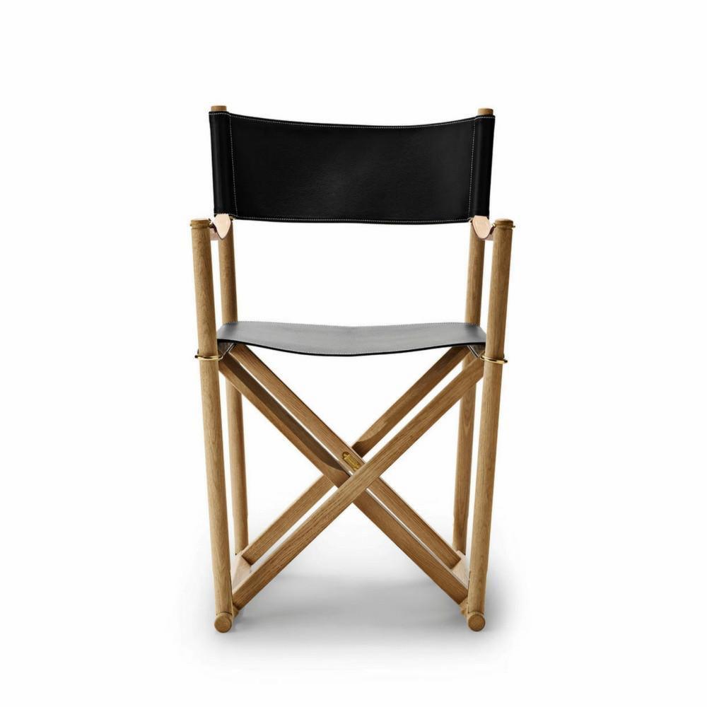 Składane krzesło reżyserskie z jasnego drewna i czarnej skóry, widok z przodu na białym tle, detale szycia na skórzanych elementach.