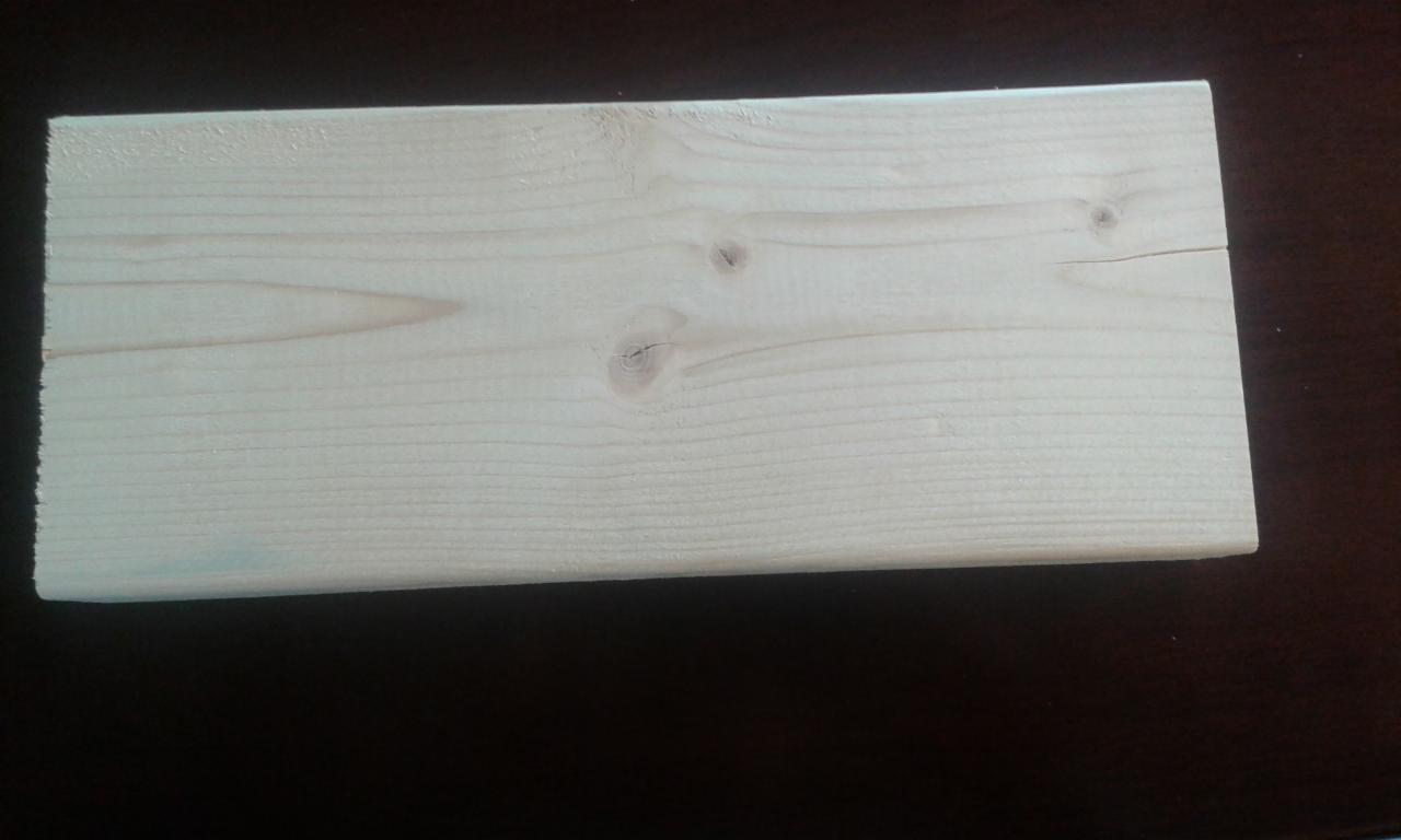 Jasna deska z widocznymi słojami i sękami, ułożona na ciemnym tle. Tarcica budowlana dostępna w Łodzi.